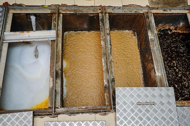 a technician cleaning a commercial kitchen's grease trap